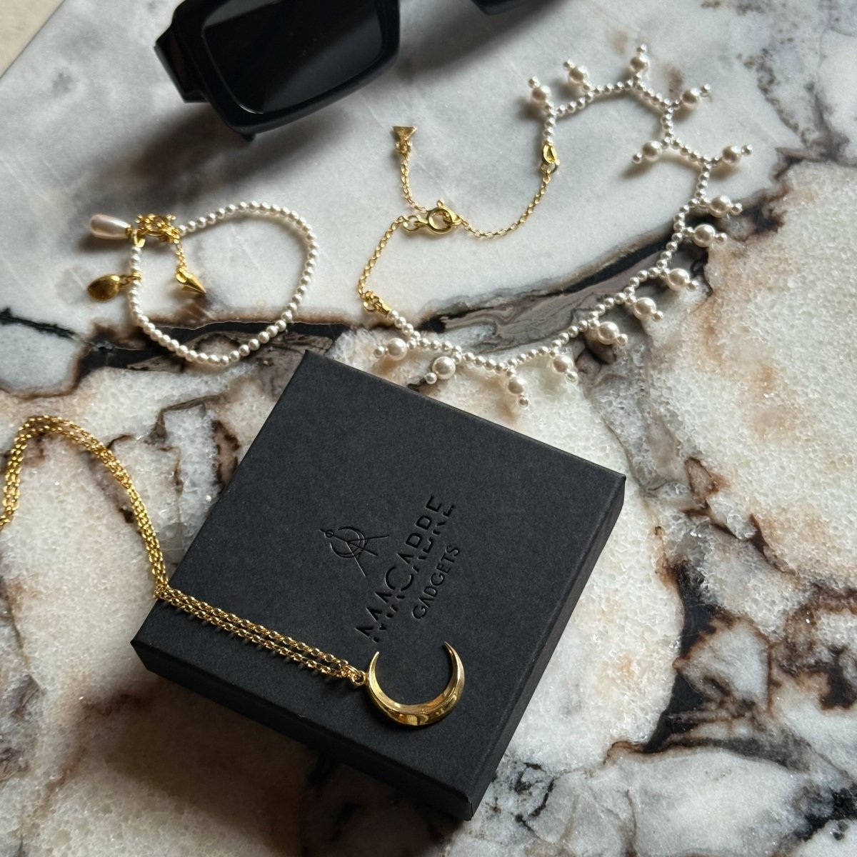 Luna pendant by Macabre Gadgets placed on a branded box, along with Sacred Pearls necklace and Pearl bracelet