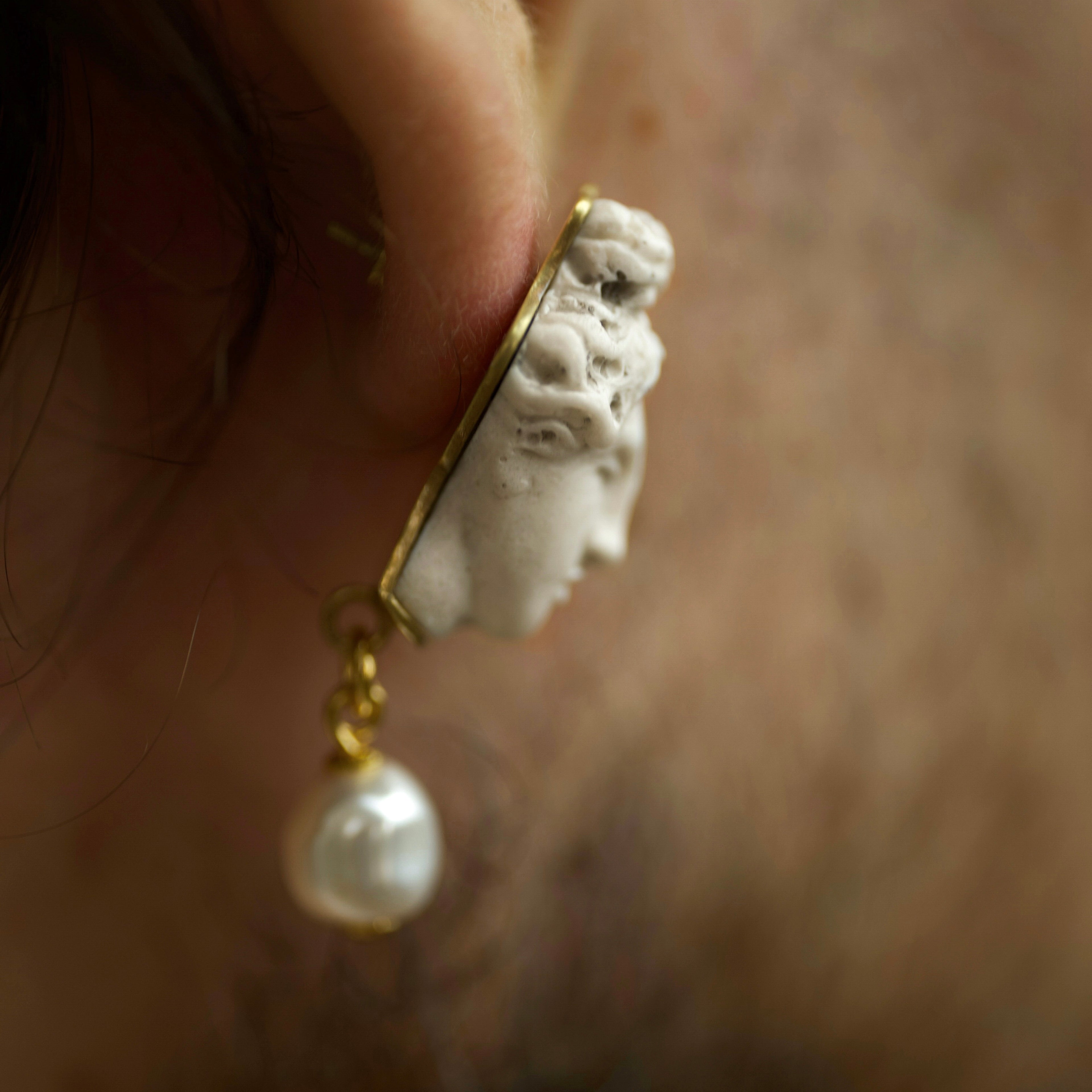 Close-up of an ear wearing Aphrodite  earring - handcrafted sculptured mythology earring