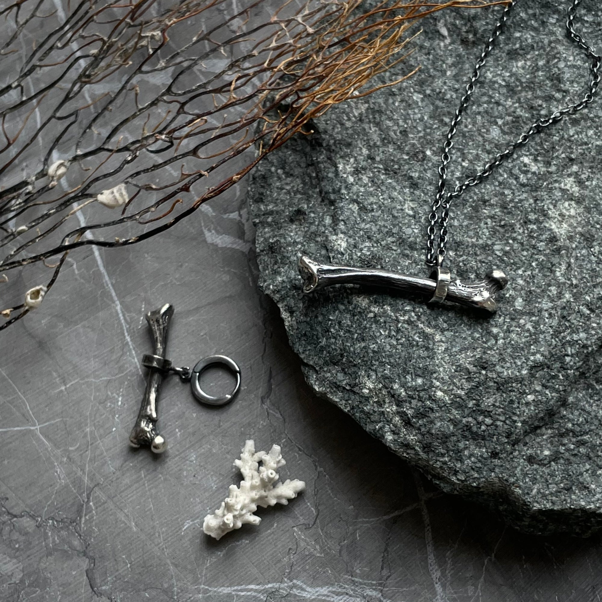 Silver Bone earring placed on a black marble 
