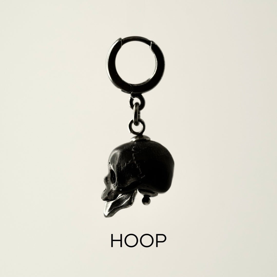 Ancient Skull earring side view showing hoop variant with sterling silver huggie clasp on neutral background