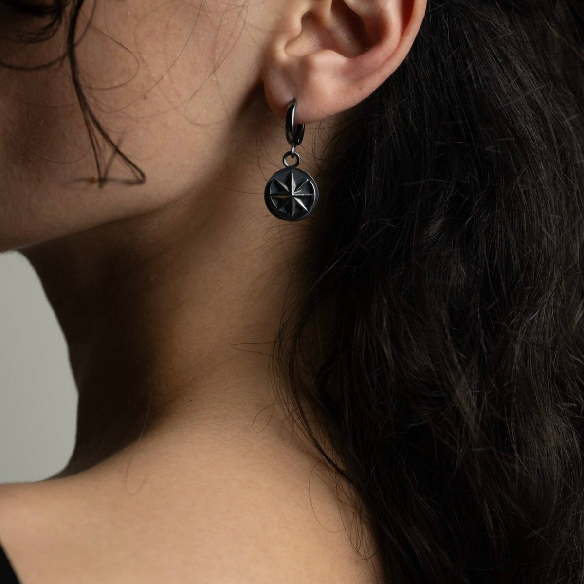 Aster earring by Macabre Gadgets on female model with long dark hair, star coin earring styling shot