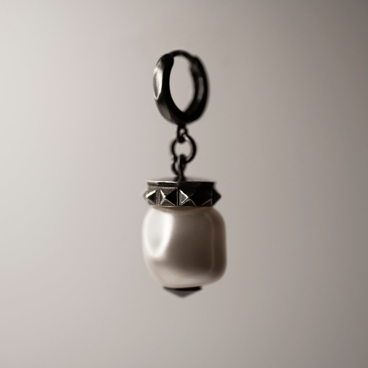 Baroque pearl earring with large baroque pearl on sterling silver huggie clasp against neutral background