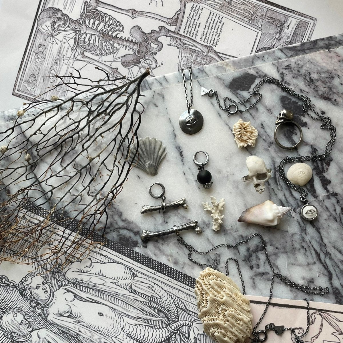 Silver Bone earring with variety skeleton inspired jewelry placed on white marble