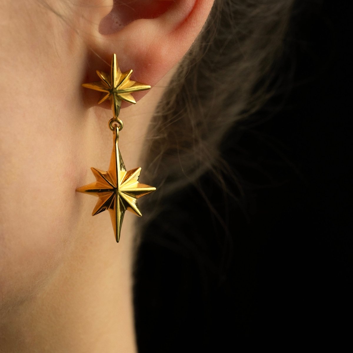 Female model wearing Castor & Pollux earring gold variant close-up, celestial twin stars jewelry lifestyle shot