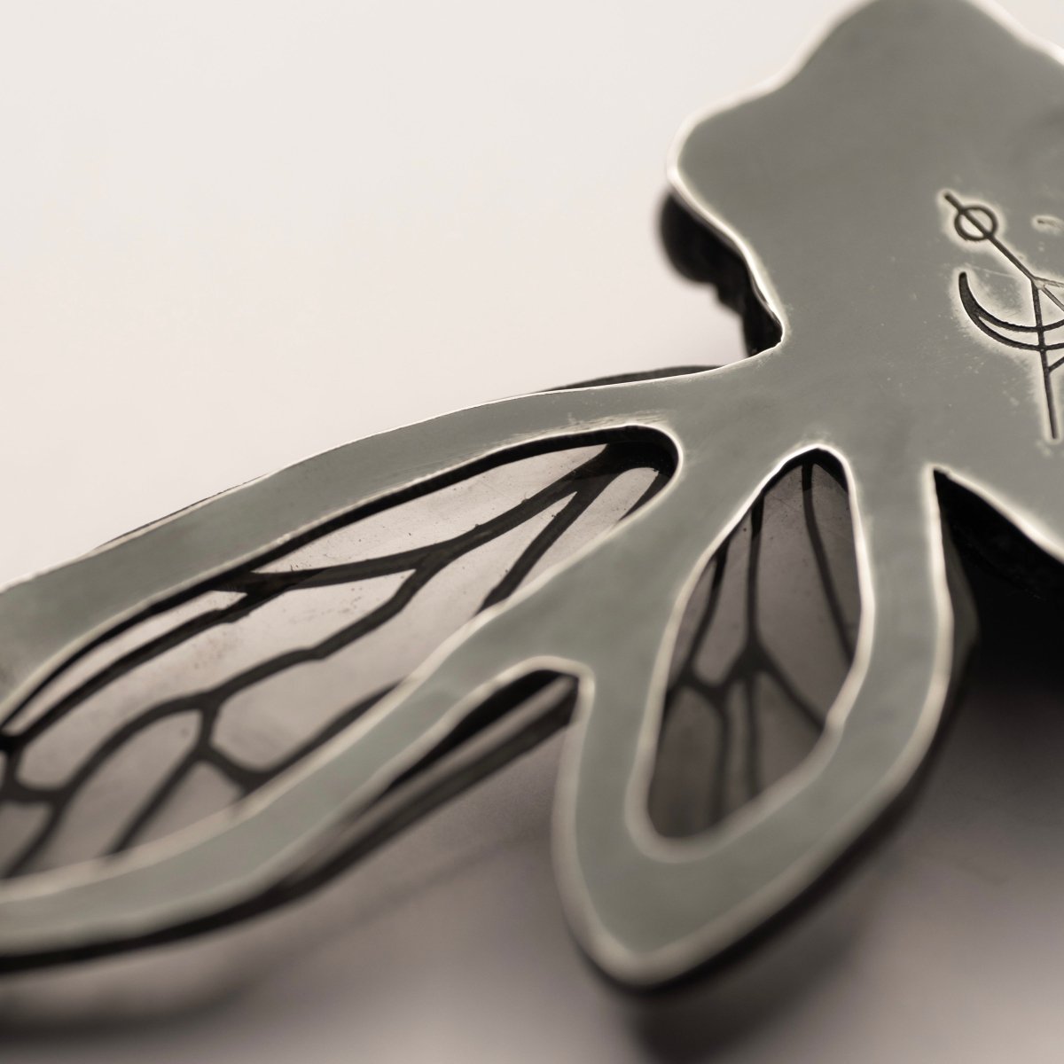 Cicada necklace - black variant - close-up of the silver back part with logo detail