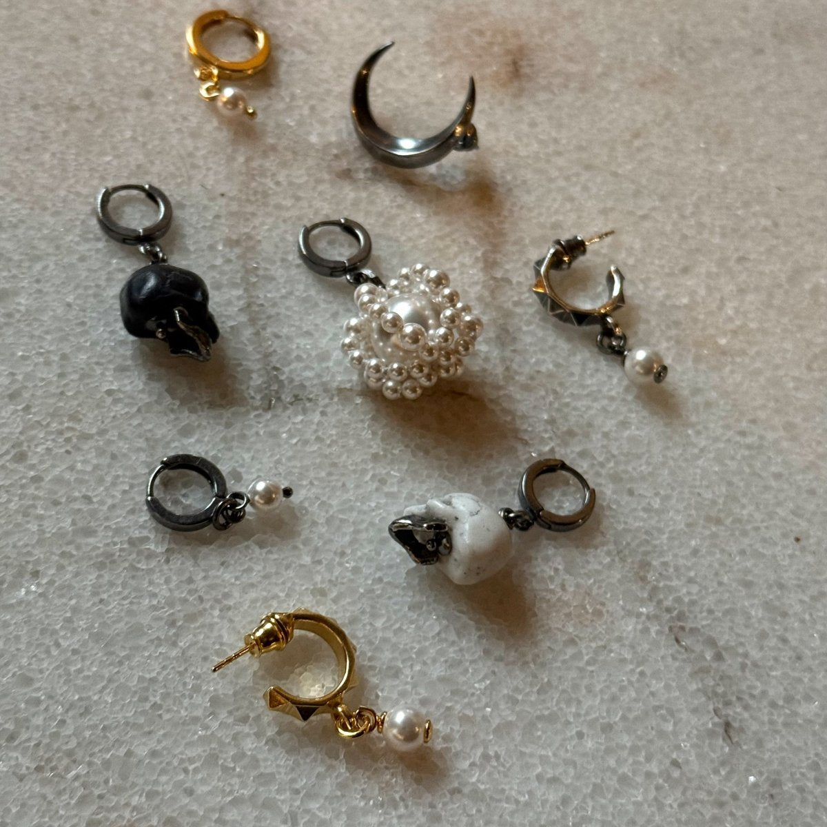 Mini pearl earring on a marble surface with the earrings by Macabre Gadgets