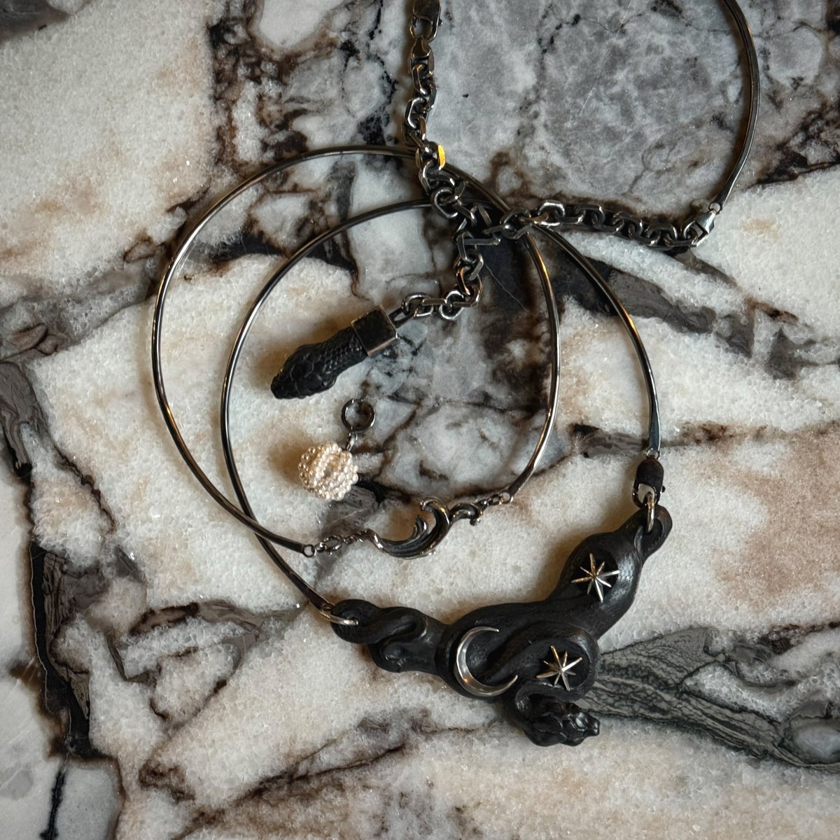 Pearl Cloud earring along with other jewelry by Macabre Gadgets on white marble surface