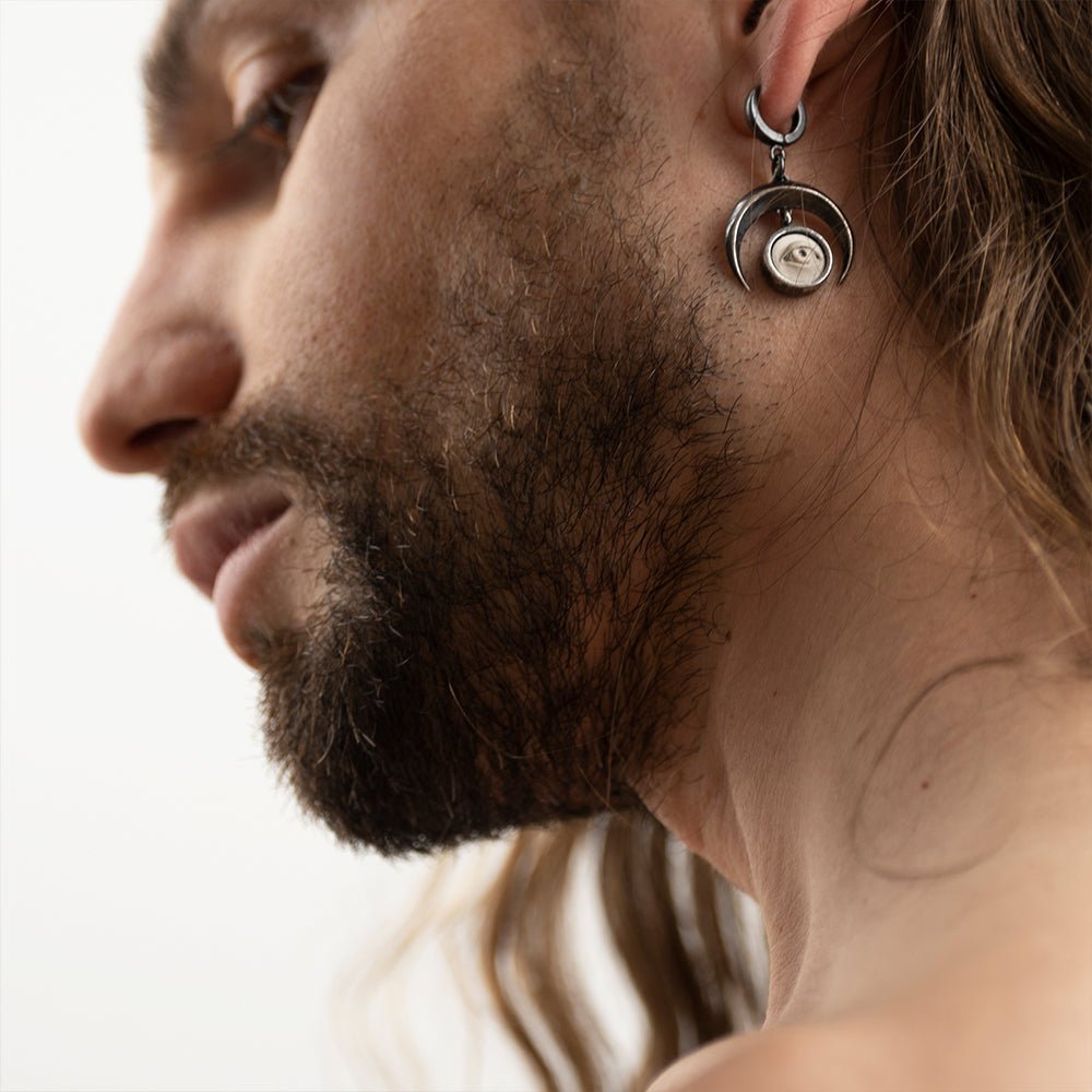 Male model with long hair wearing Crescent Oracle earring, gothic moon and eye jewelry lifestyle photography