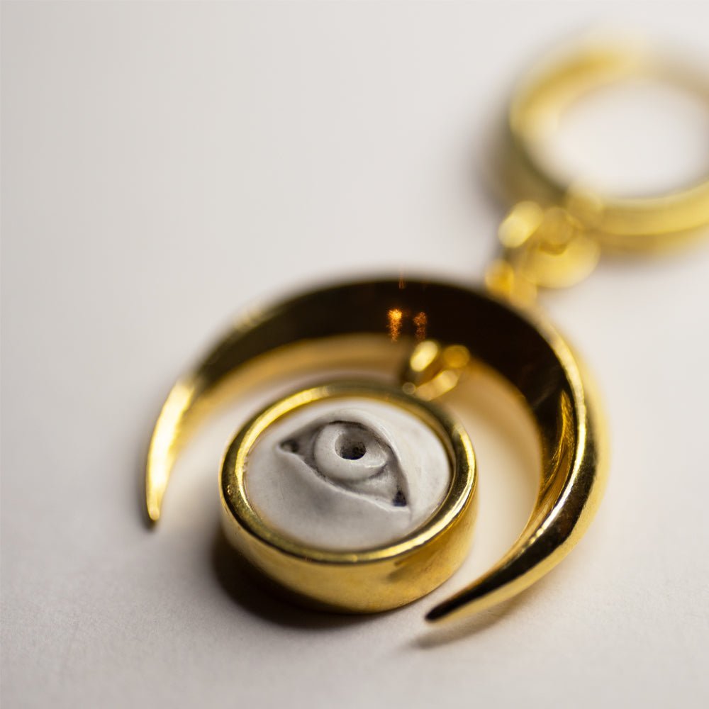 Crescent Oracle earring close-up of gold plated bezel holder with marble eye cameo relief