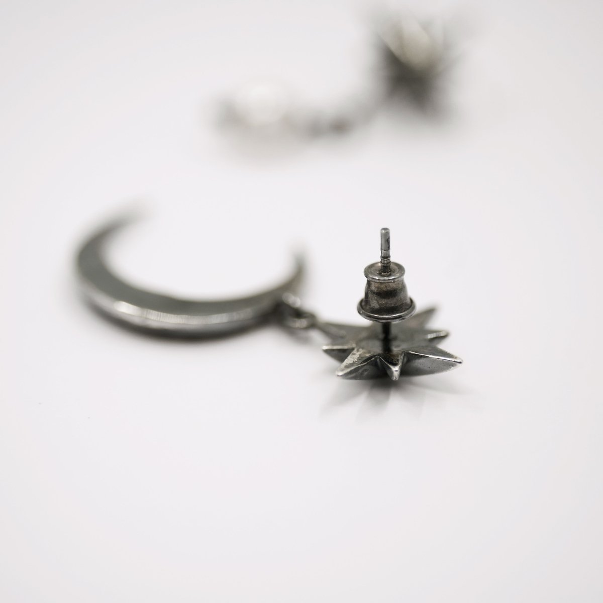 Dusk earring on white surface demonstrating sterling silver stud lock mechanism