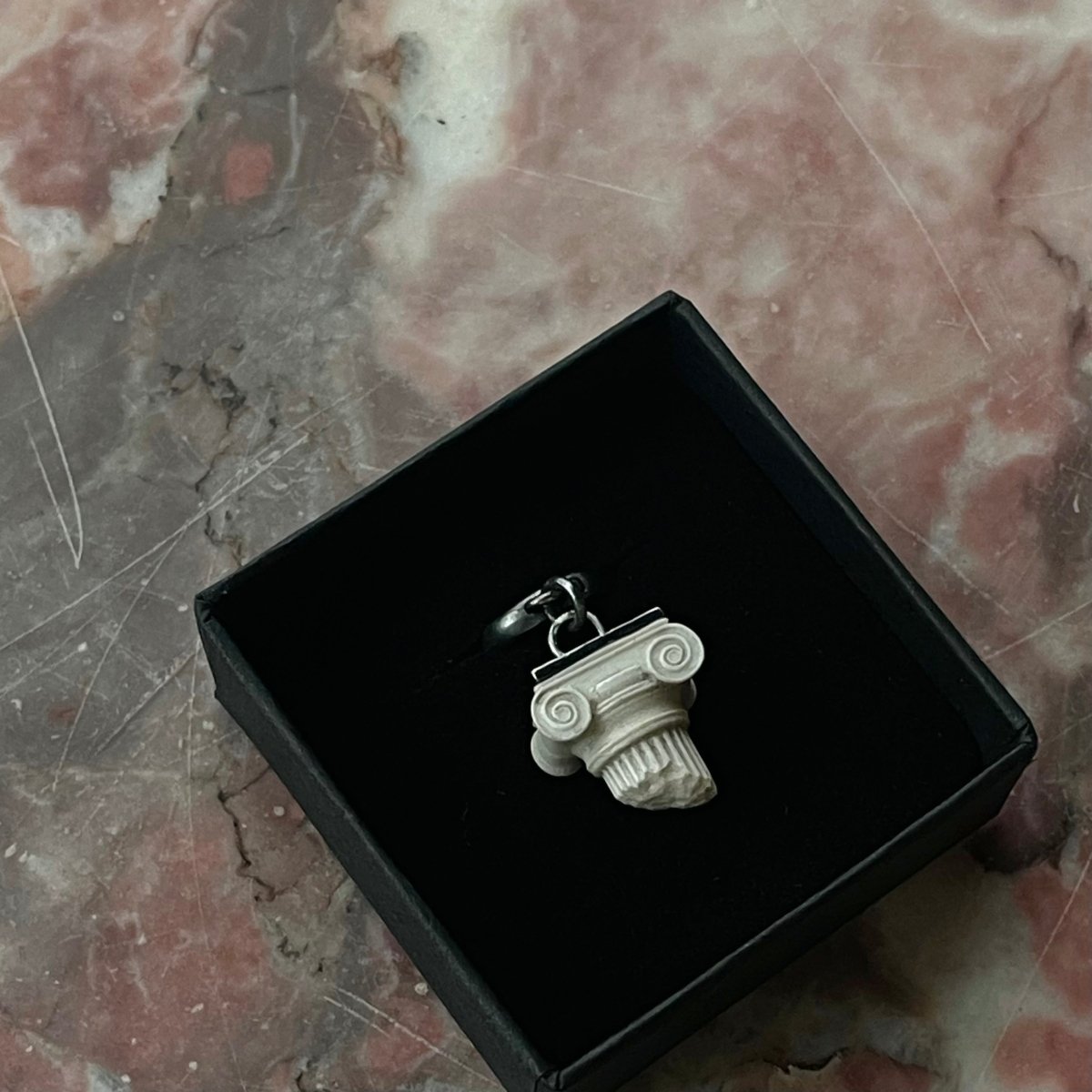 Ionic earring in black jewelry box on pink marble surface, Greek architecture inspired jewelry presentation