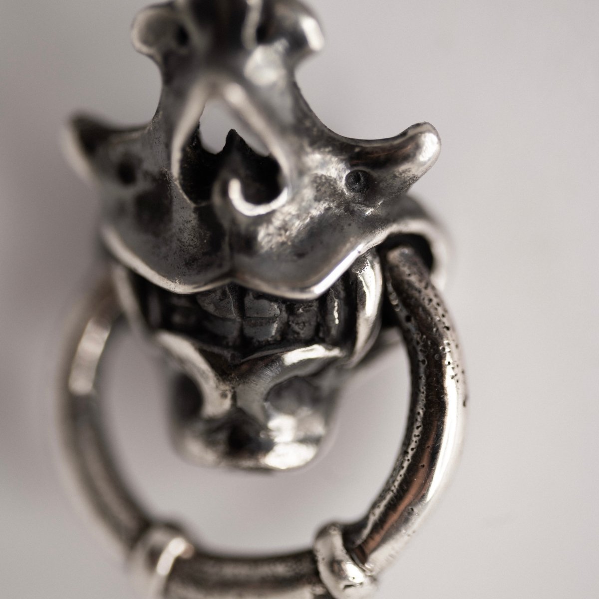 Silver Mask earring close up with focus on a decorative details