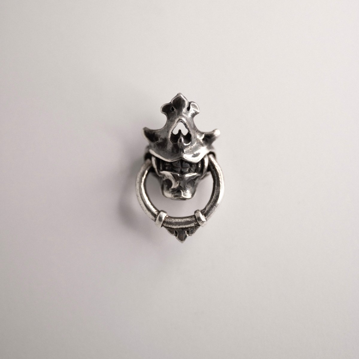 Silver Mask earring placed against white background
