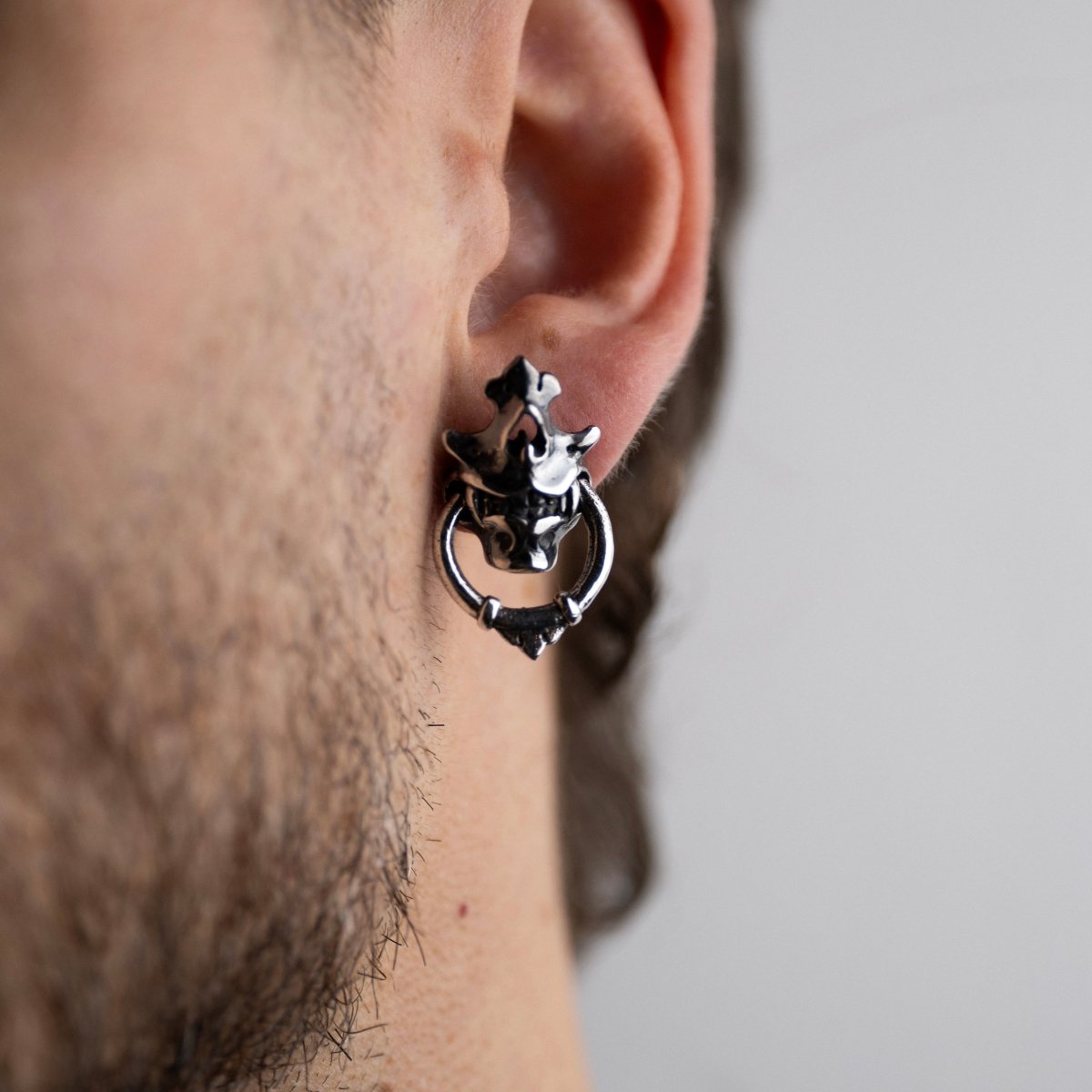 Silver Mask earring on a male model with a beard