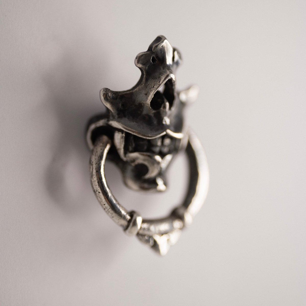 Silver Mask earring placed against white background from the side