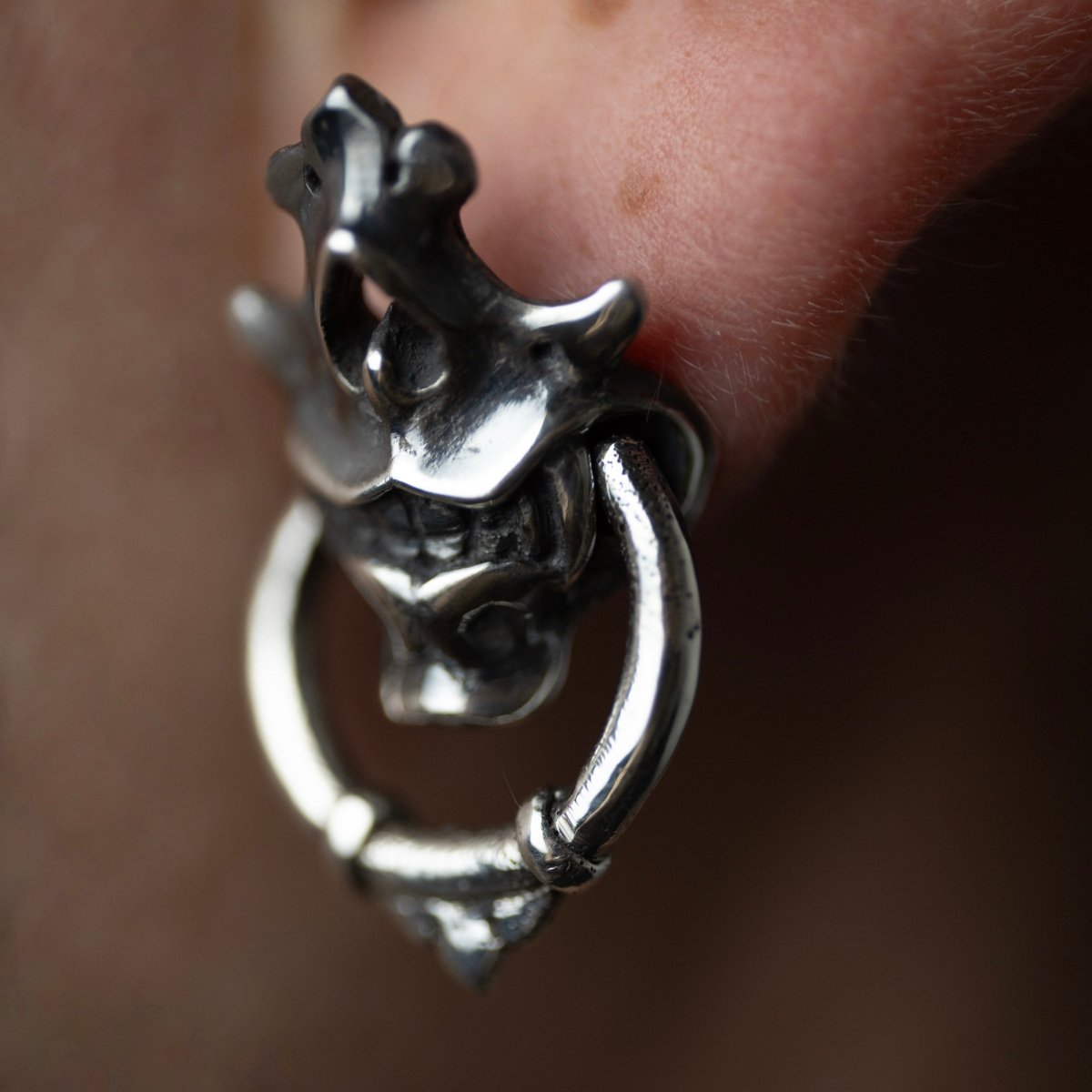 Silver Mask earring close up on a earlobe