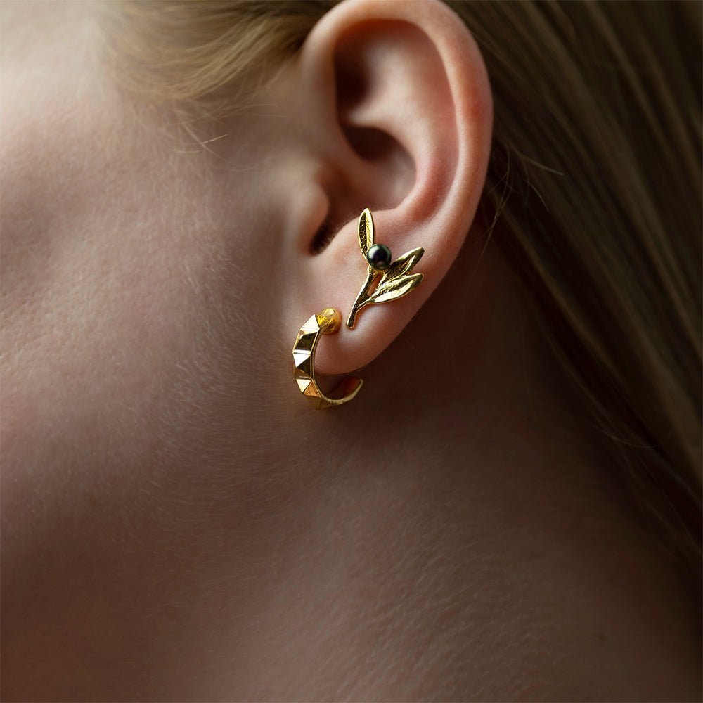 Female model with blonde hair wearing Olive Branch earring gold variant close-up, botanical jewelry lifestyle shot