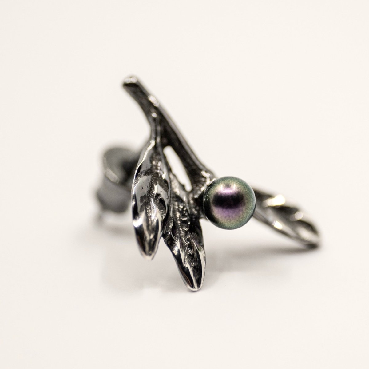 Olive Branch earring - close-up of floral stud earrings with sterling silver leafs and black pearl on neutral background
