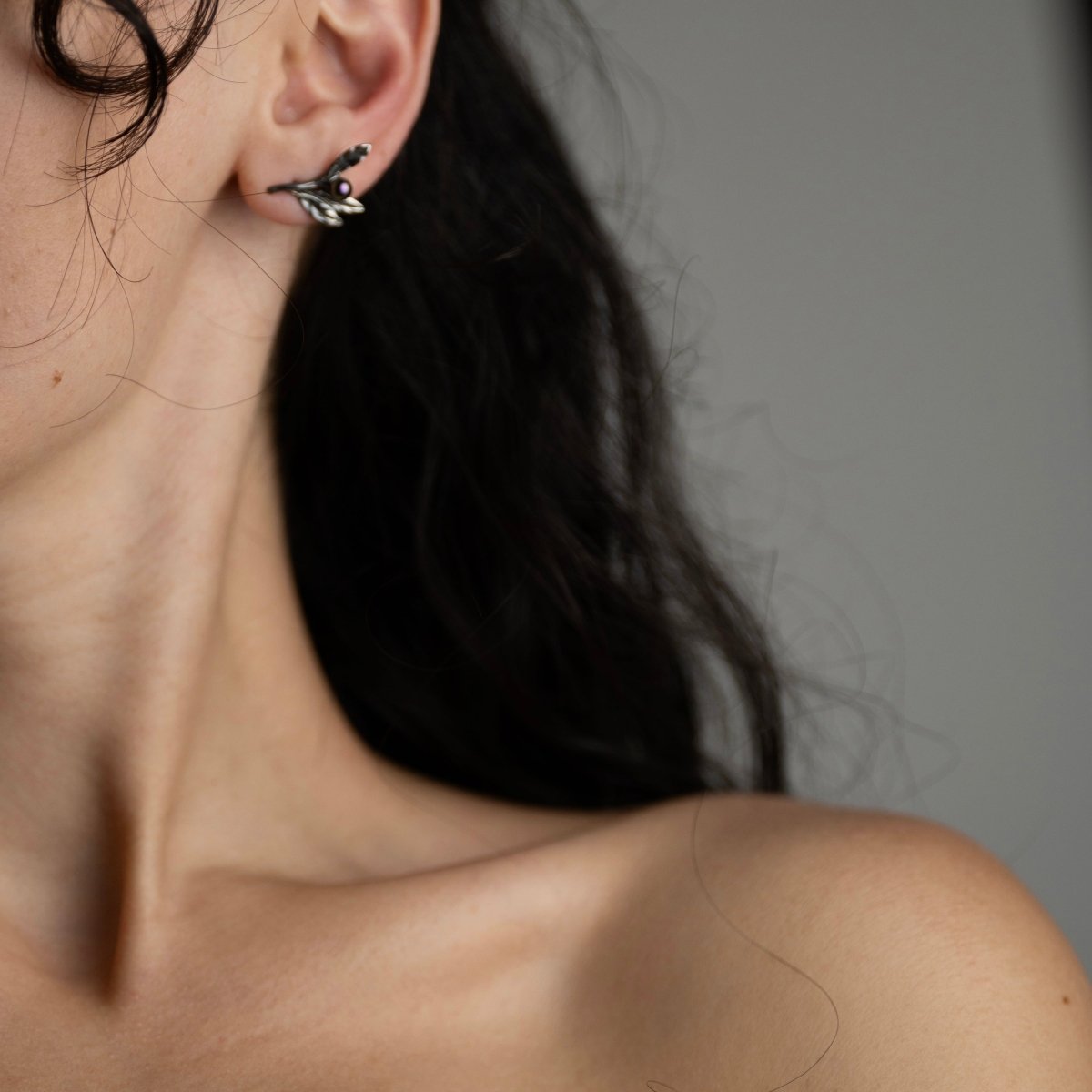 Female model with black hair wearing Olive Branch earring silver variant, handcrafted botanical jewelry lifestyle photography