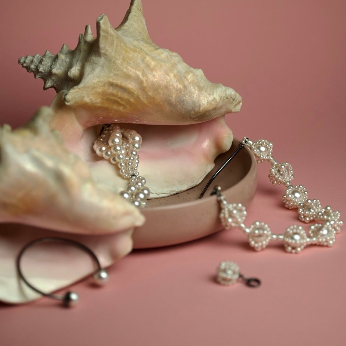 Pearl Cloud earring, Pearl Cloud necklace and other jewelry by Macabre Gadgets placed on a sea shells on pink background