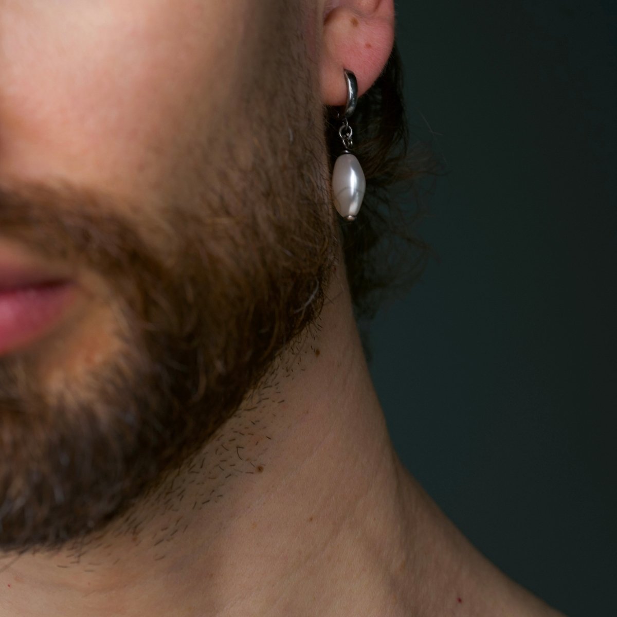 Bearded male model wearing Pearl Coin earring with sterling silver hoop on dark background, jewelry lifestyle shot
