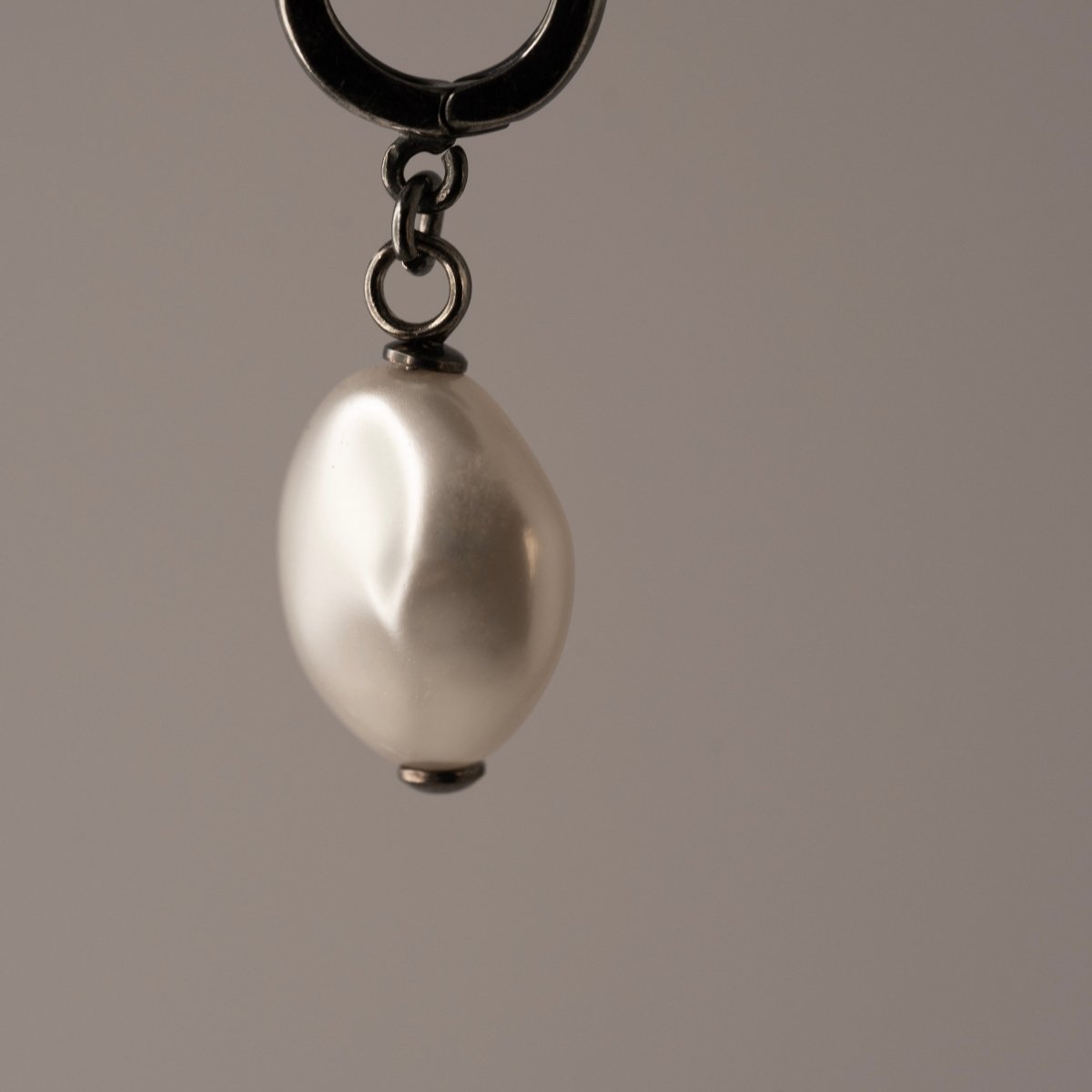 Pearl Coin earring close-up showing glass pearl and sterling silver huggie clasp connection