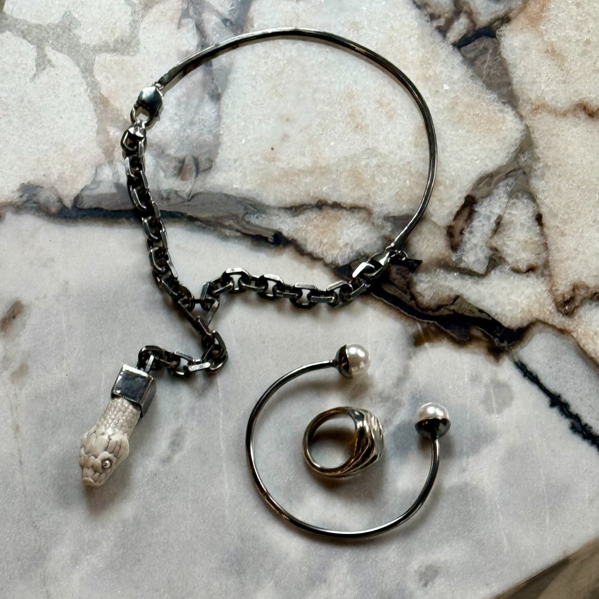 Pearl cuff bracelet with other jewelry on white marble surface