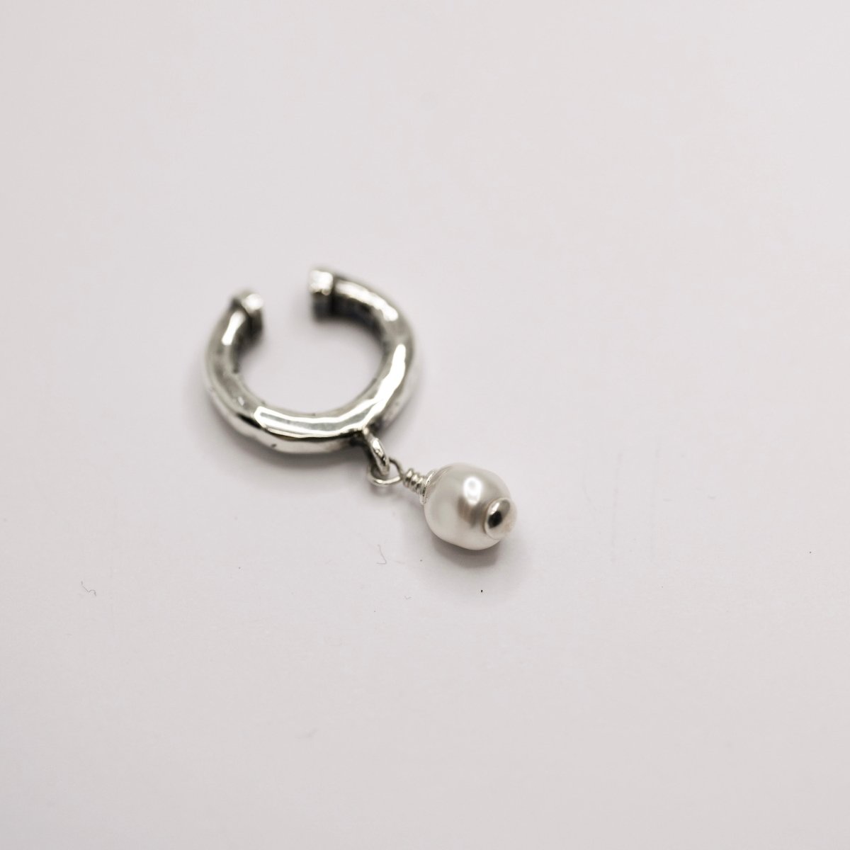 Pearl ear cuff by Macabre Gadgets on neutral surface showing sterling silver and glass pearl detail, no piercing required jewelry