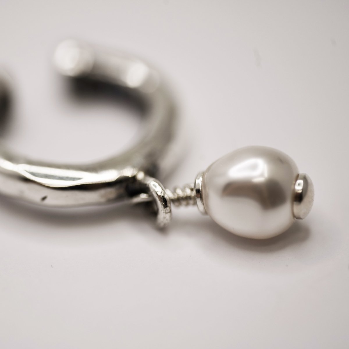 Pearl ear cuff close-up showing glass pearl and sterling silver fixture connection, handcrafted jewelry detail