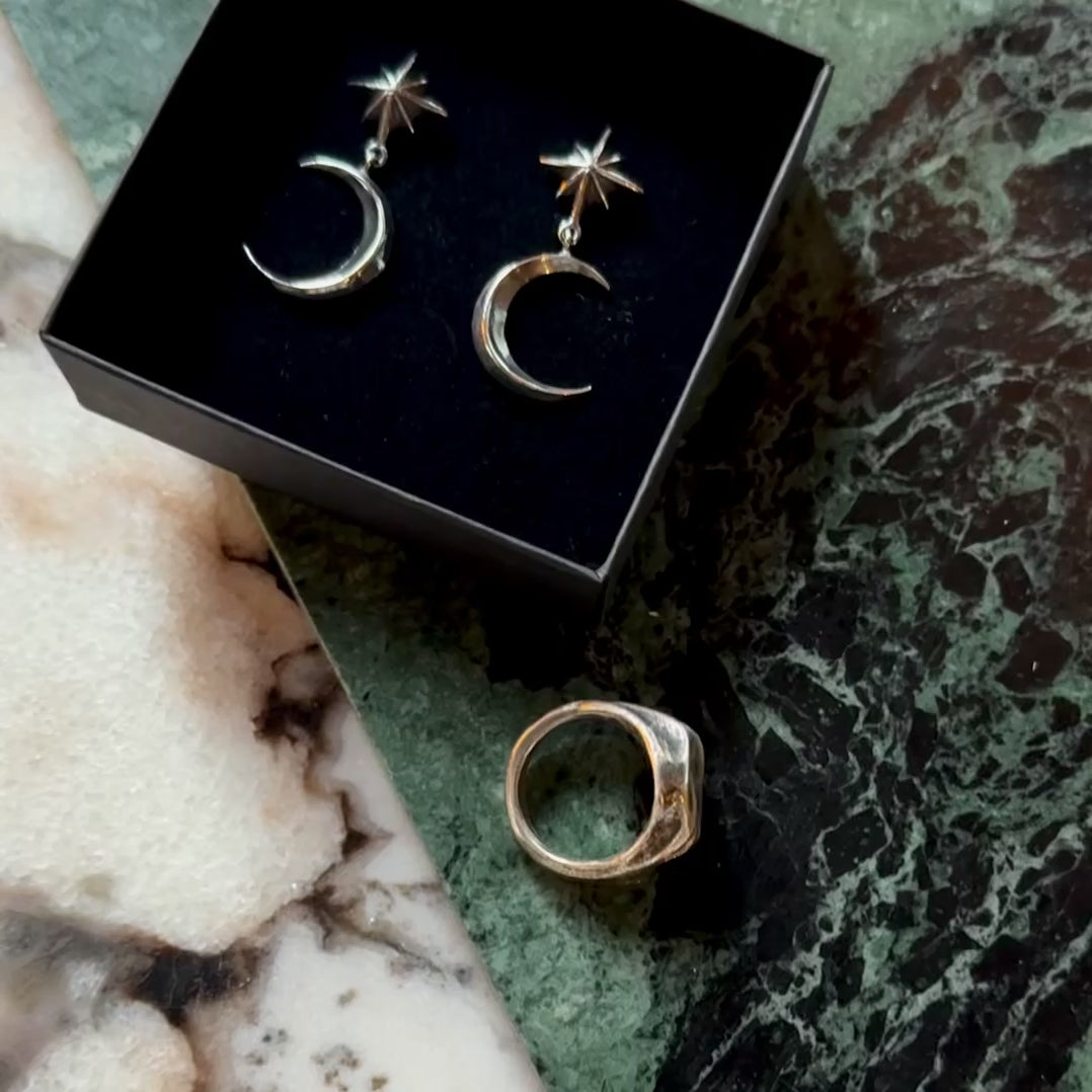 Dusk earring in a black jewelry box, on a green marble surface