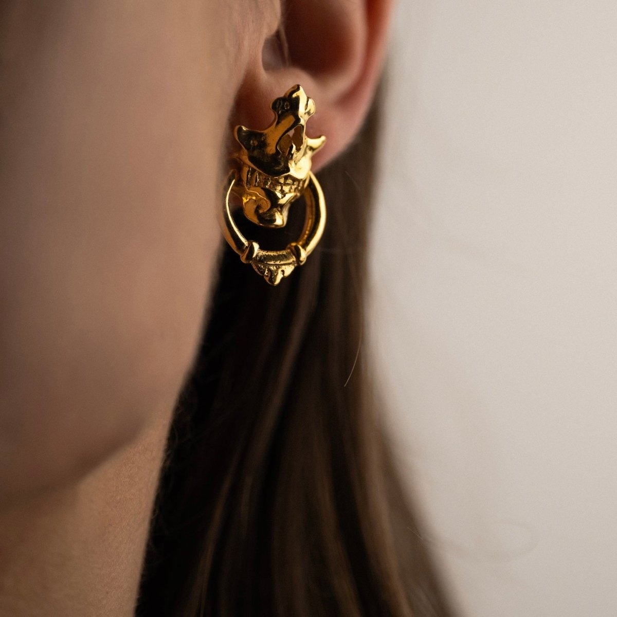 Silver Mask earring in gold plating on a female model with long hair
