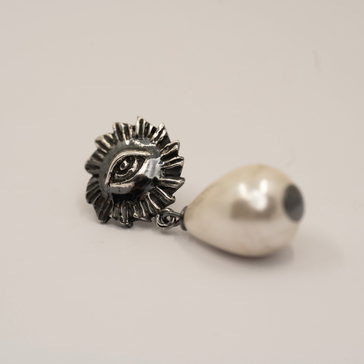 Sirius Pearl Drop earring on white surface showing detailed eye relief design, handcrafted sterling silver gothic earring