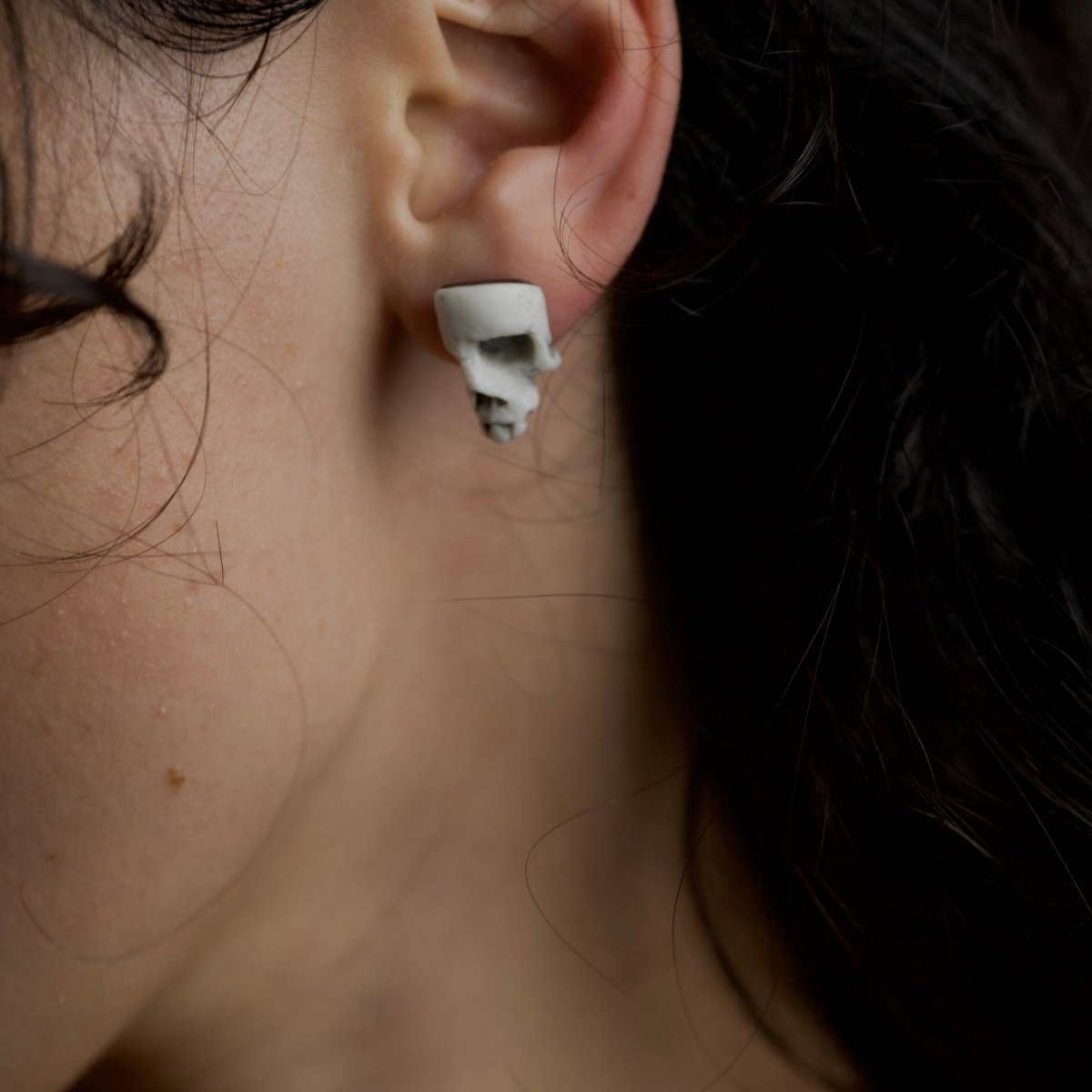 Skull Fragment earring on a female model with dark hair, lifestyle shoot