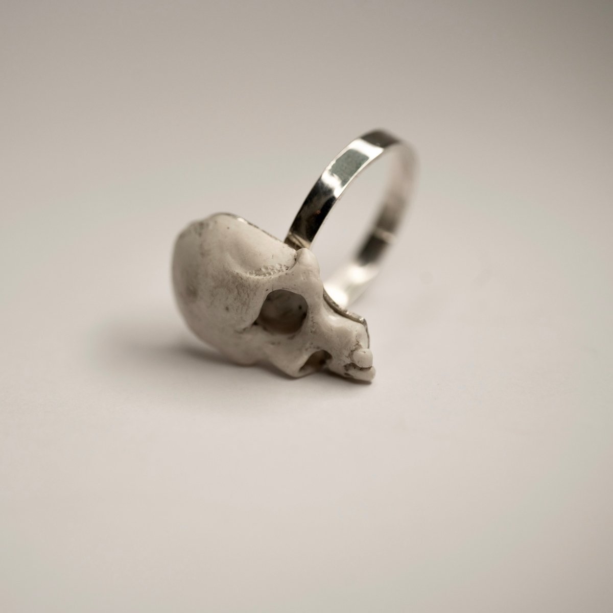 Skull Fragment ring on its side, on a white surface, semi side view