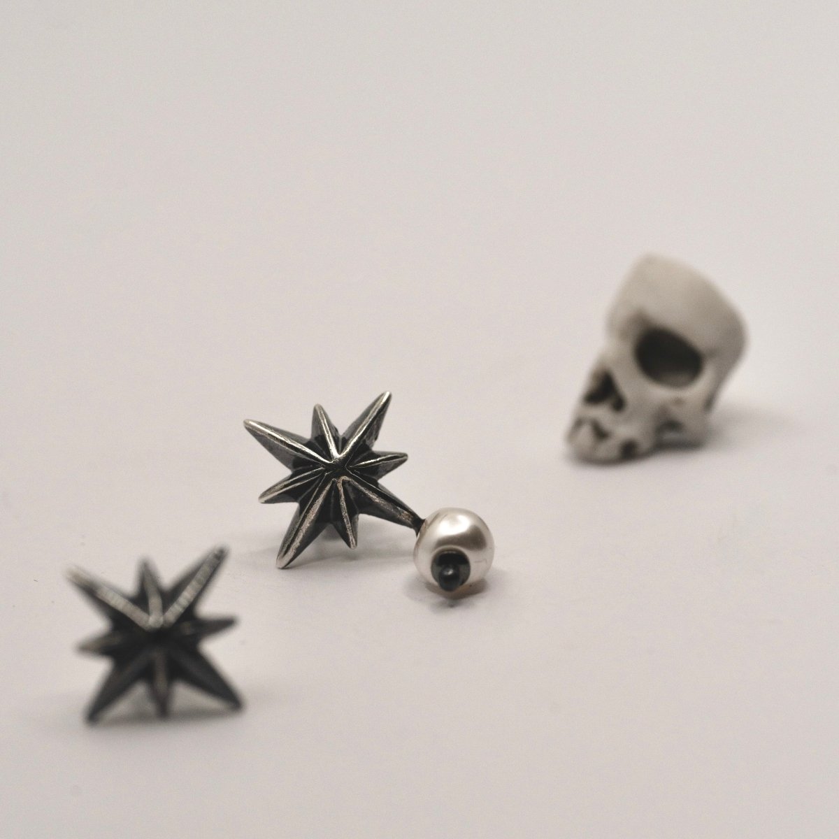 Star & Pearl earring along with other jewelry by Macabre Gadgets on a white surface
