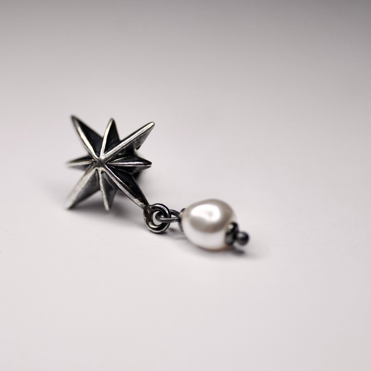 Star & Pearl earring on a white background, shows the pearl detail and its fixture to the star element