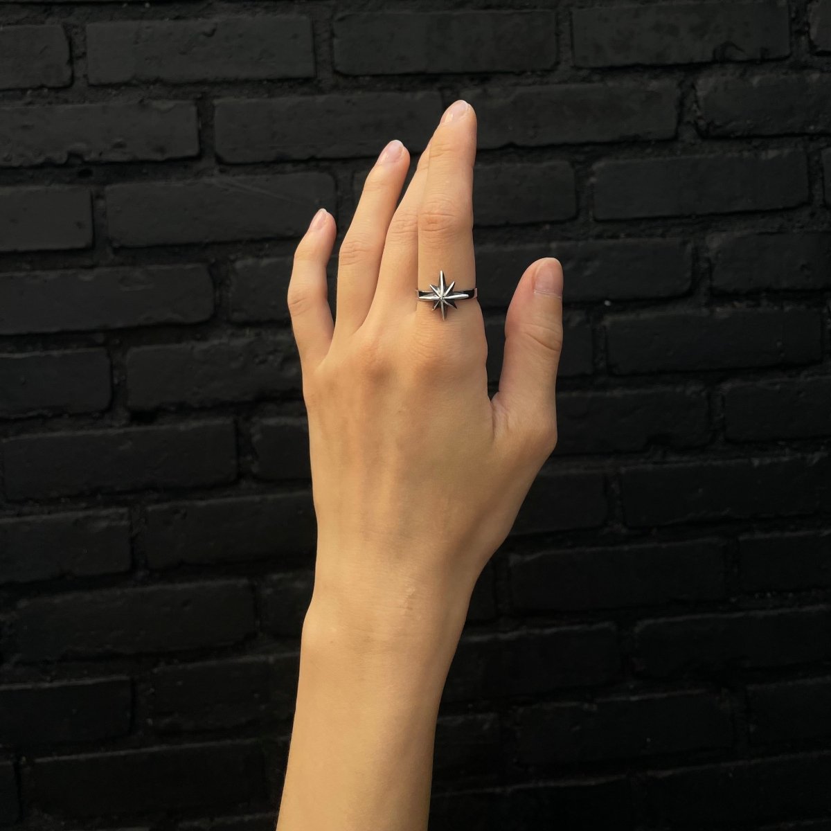 Star ring on a woman's hand, index finger, against black background