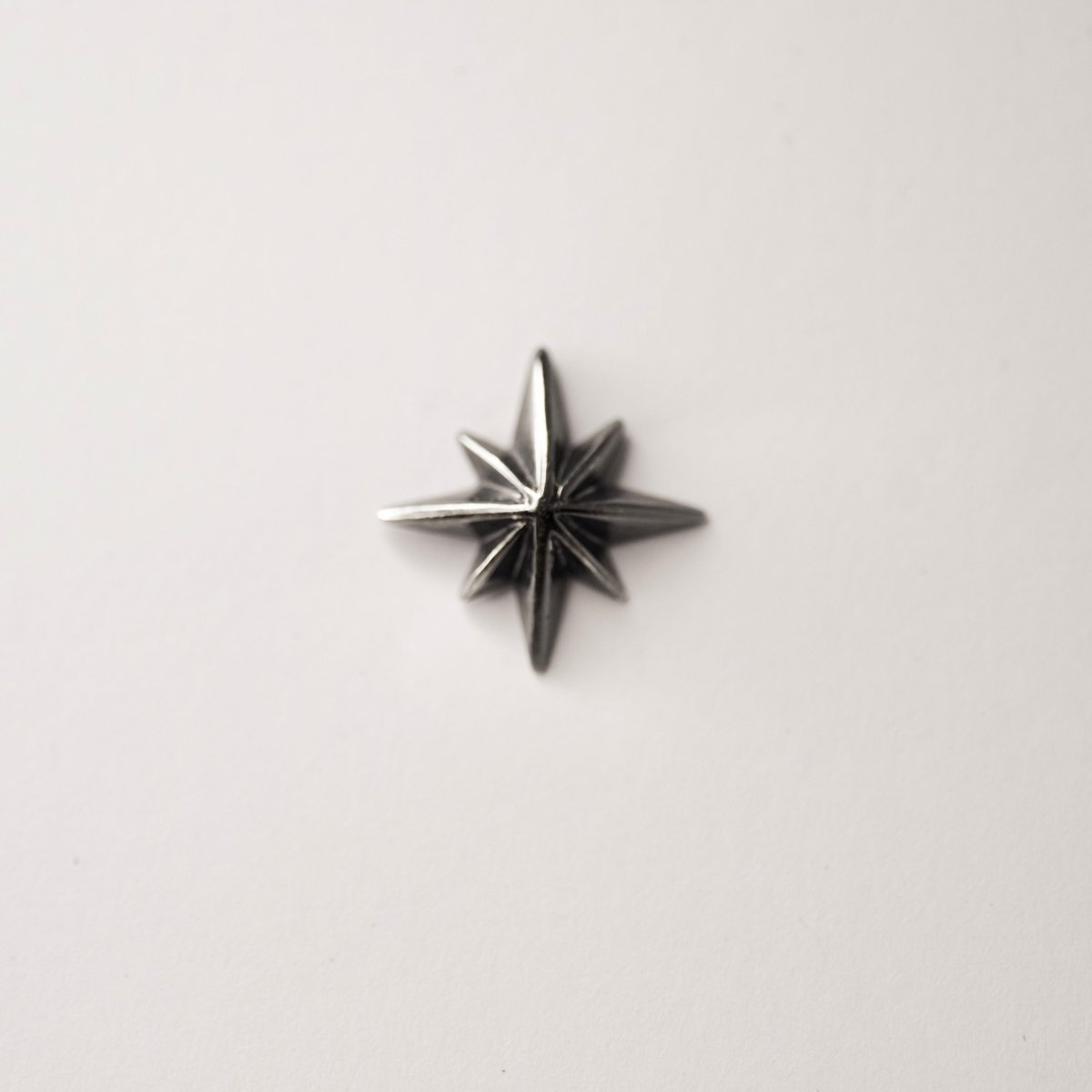 Star stud earring - silver variant - front view of star-shaped earring on a neutral background
