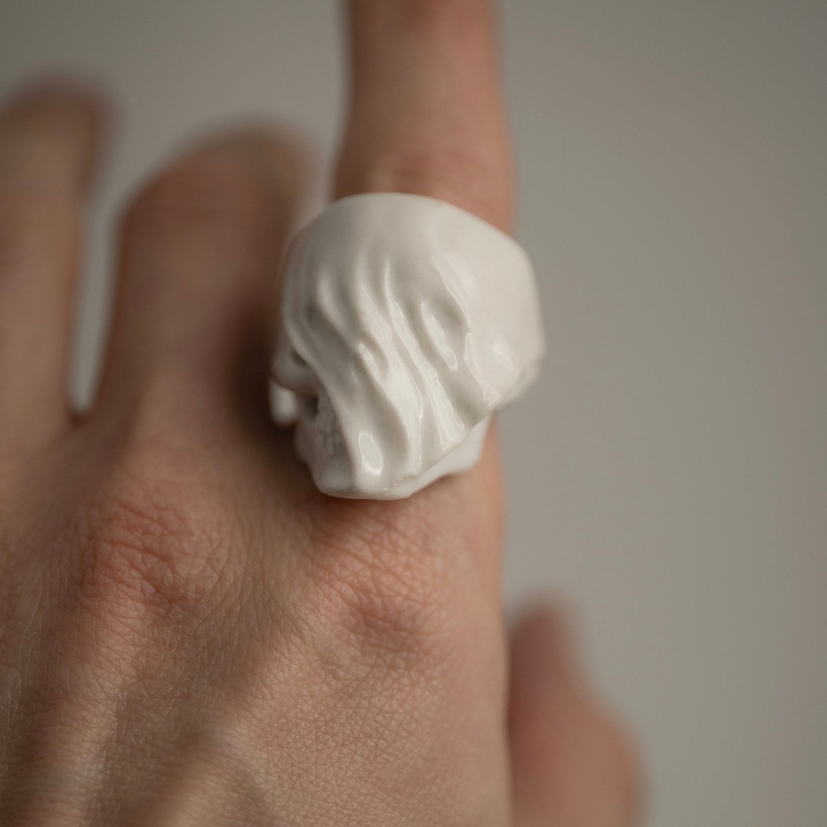 Veiled Skull ring - on a model's hand, colour palette of this image mostly pastel which creates a nice contrast with dark symbolism of the ring