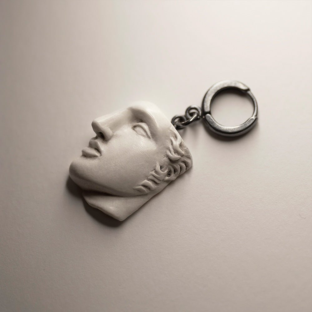 Achilles earring with bonded marble sculpture of male face attached to sterling silver huggie clasp on neutral background, Greek mythology jewelry