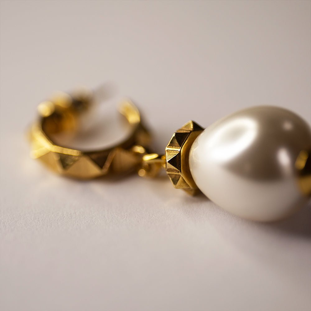 Aeon Pearl Drop earring -large gleaming pearl with gold plated silver details on beige surface