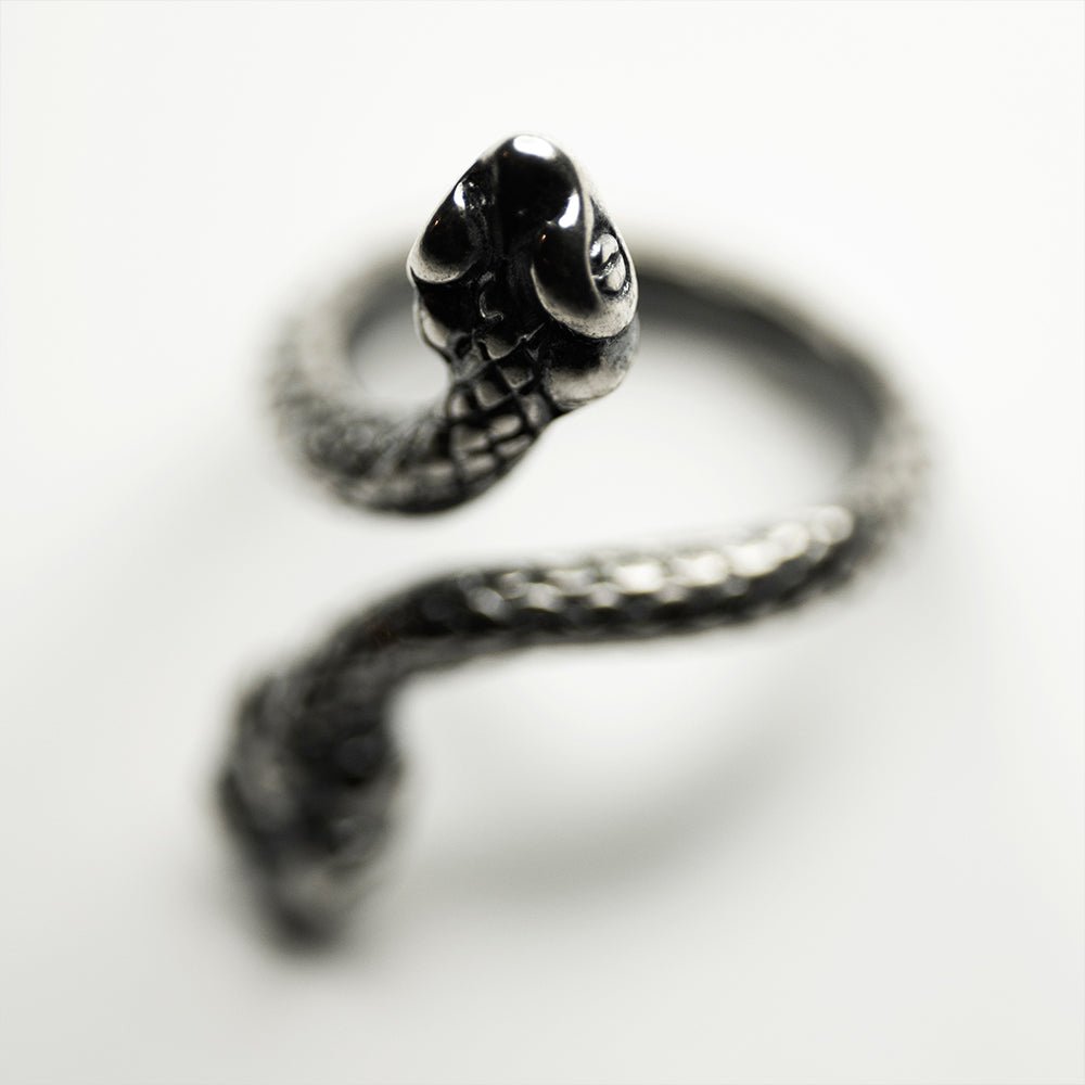 Two Headed Snake ring on a white surface, scales on snake's body and head are gleaming in semi shadow
