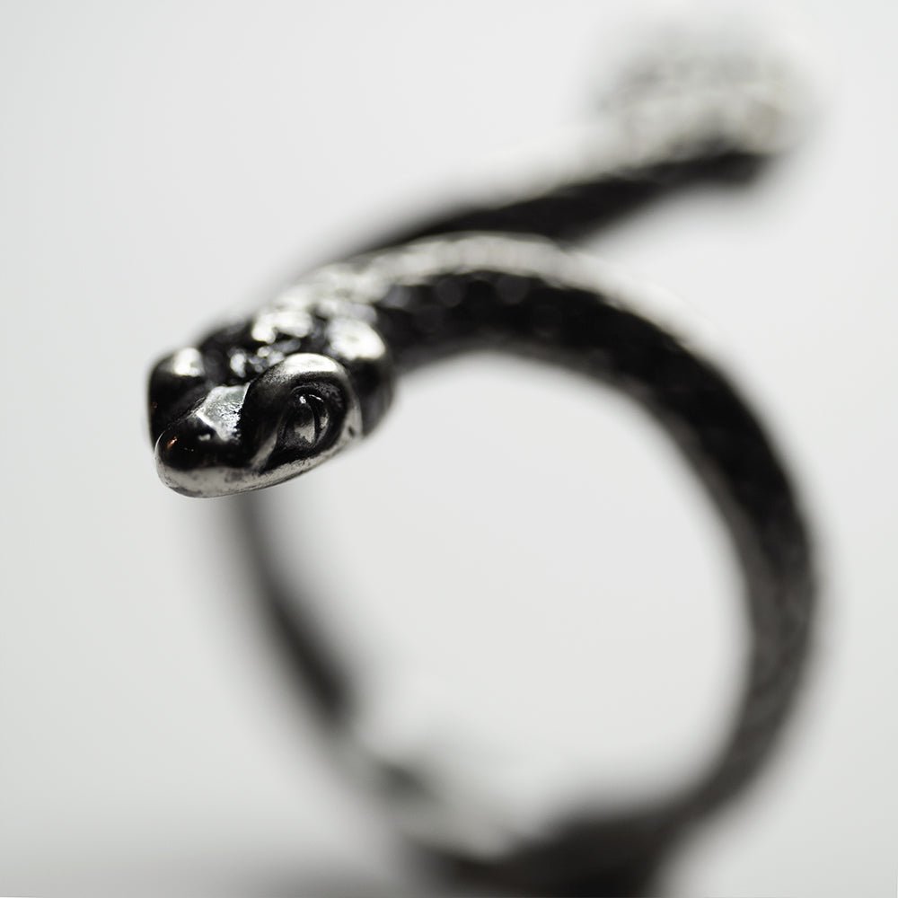Two Headed Snake ring against white background, focus on one head, the rest of the ring is blurry