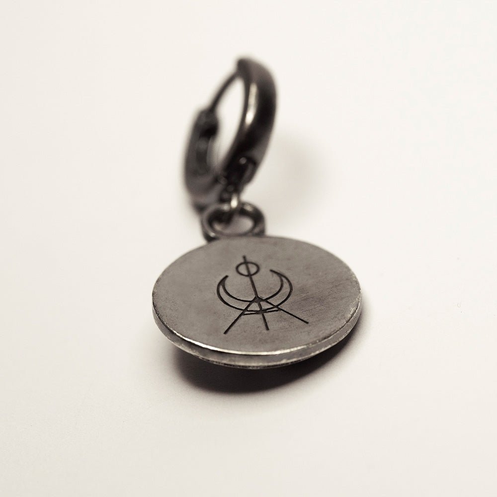 Aster earring - oxidised silver coin earring in huggie clasp with Macabre Gadgets logo on visible side