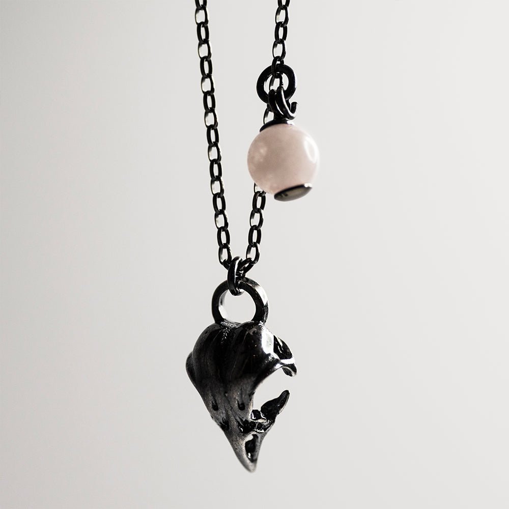 Bird skull charm-pendant against white background - charm, quarts bead and anchor chain are visible