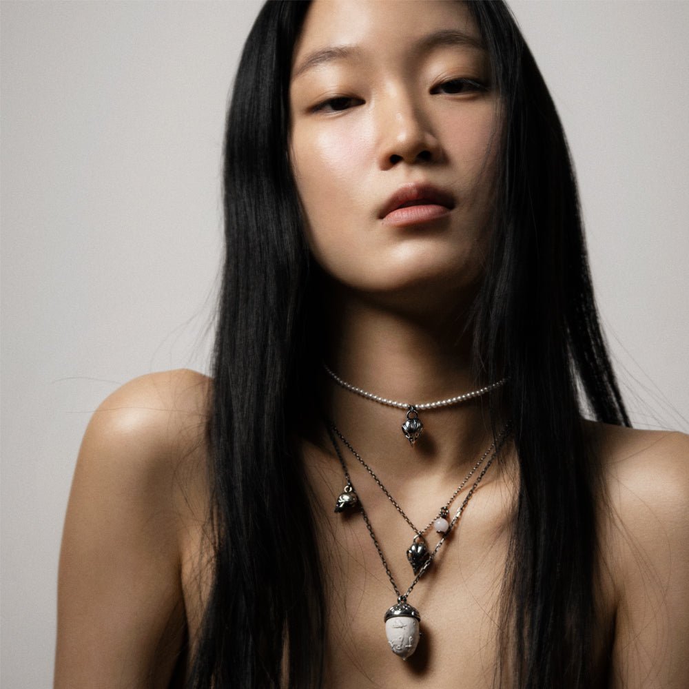 Bird skull charm-pendant on an asian female model, along with other chain necklaces by Macabre Gadgets