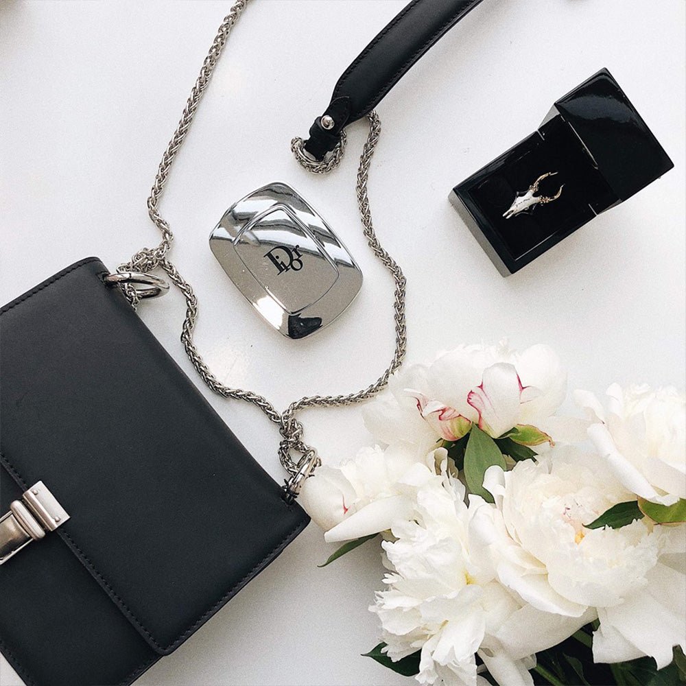 Doe ring in a jewelry box on a white surface with perfume bottle, a handbag and a flower, lifestyle editorial