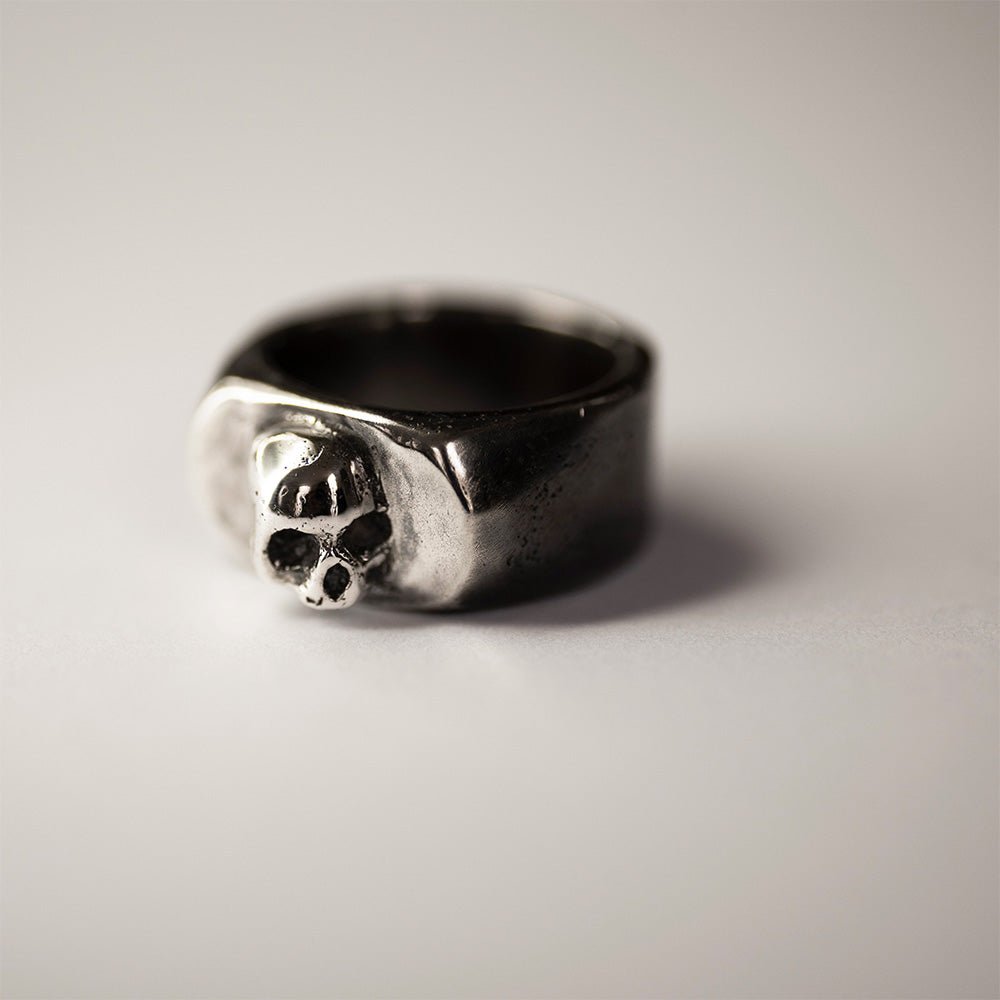 Flow ring - sterling silver skull ring on white surface