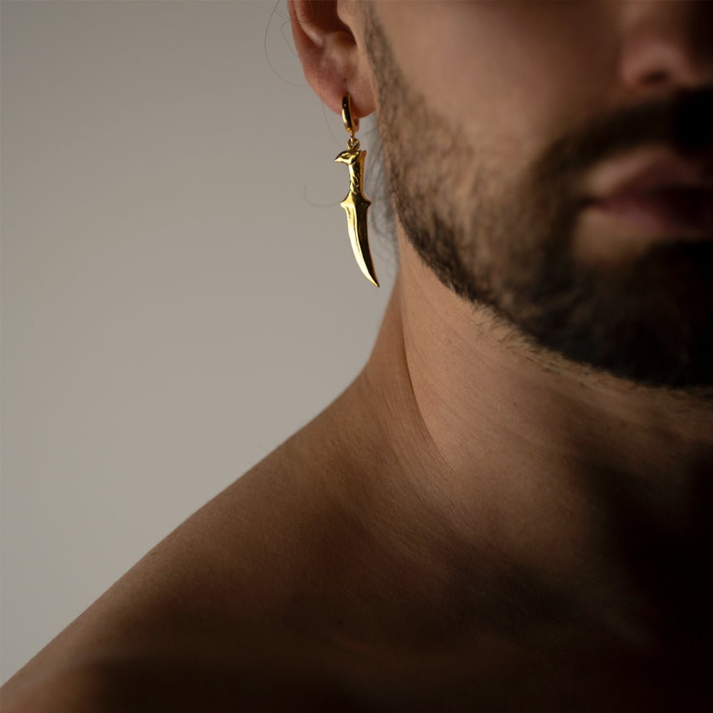 Male model wearing Griffin Sabre earring gold variant, handcrafted fantasy medieval jewelry lifestyle photography