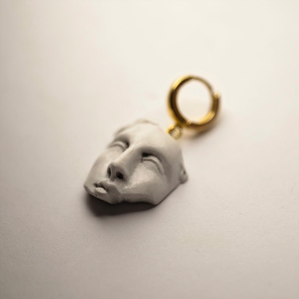 Helen earring - marble sculpted earring with gold plated hoop clasp on a white surface